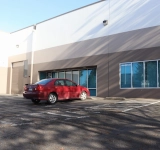 Exterior of a commercial warehouse with a red vehicle parked by the entrance.