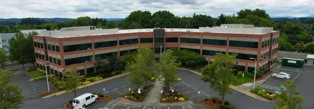 Aerial view of a three-story office building and parking lot.