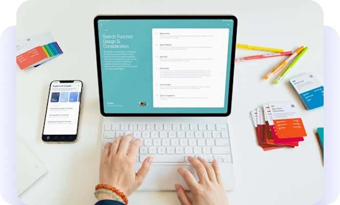 Electronic-new photo Person using a tablet and keyboard beside a phone, colorful cards, and pencils.