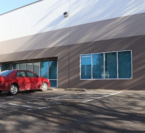 Exterior of a commercial warehouse with a red vehicle parked by the entrance.