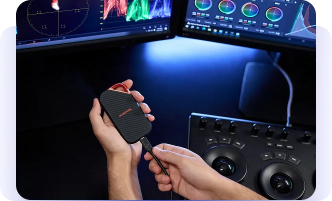 Hands connecting a portable drive to a video-editing workstation.