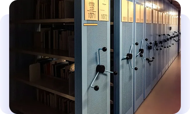 Rows of compact mobile shelving for archival storage, with hand-crank controls.