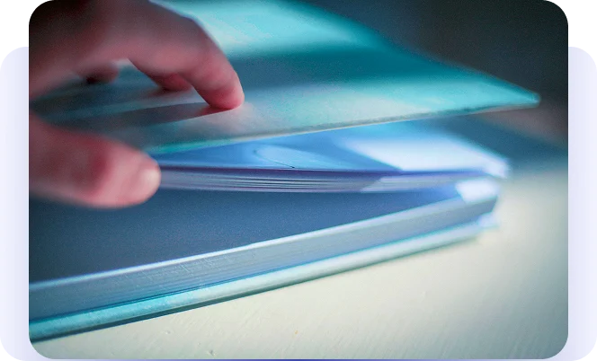 Hand lifting the cover of a stack of document folders.